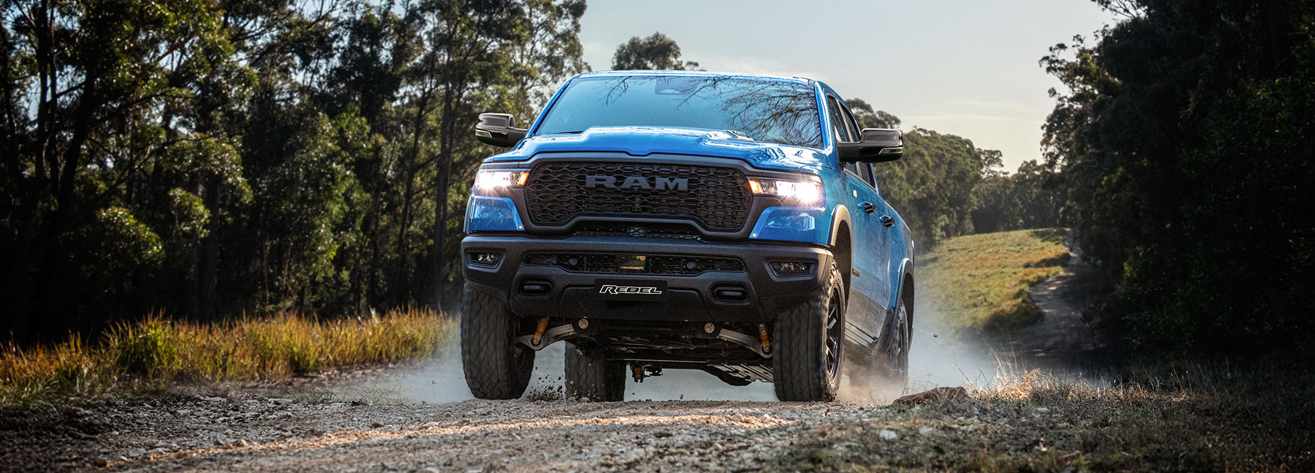 A blue RAM truck driving on a dirt road
